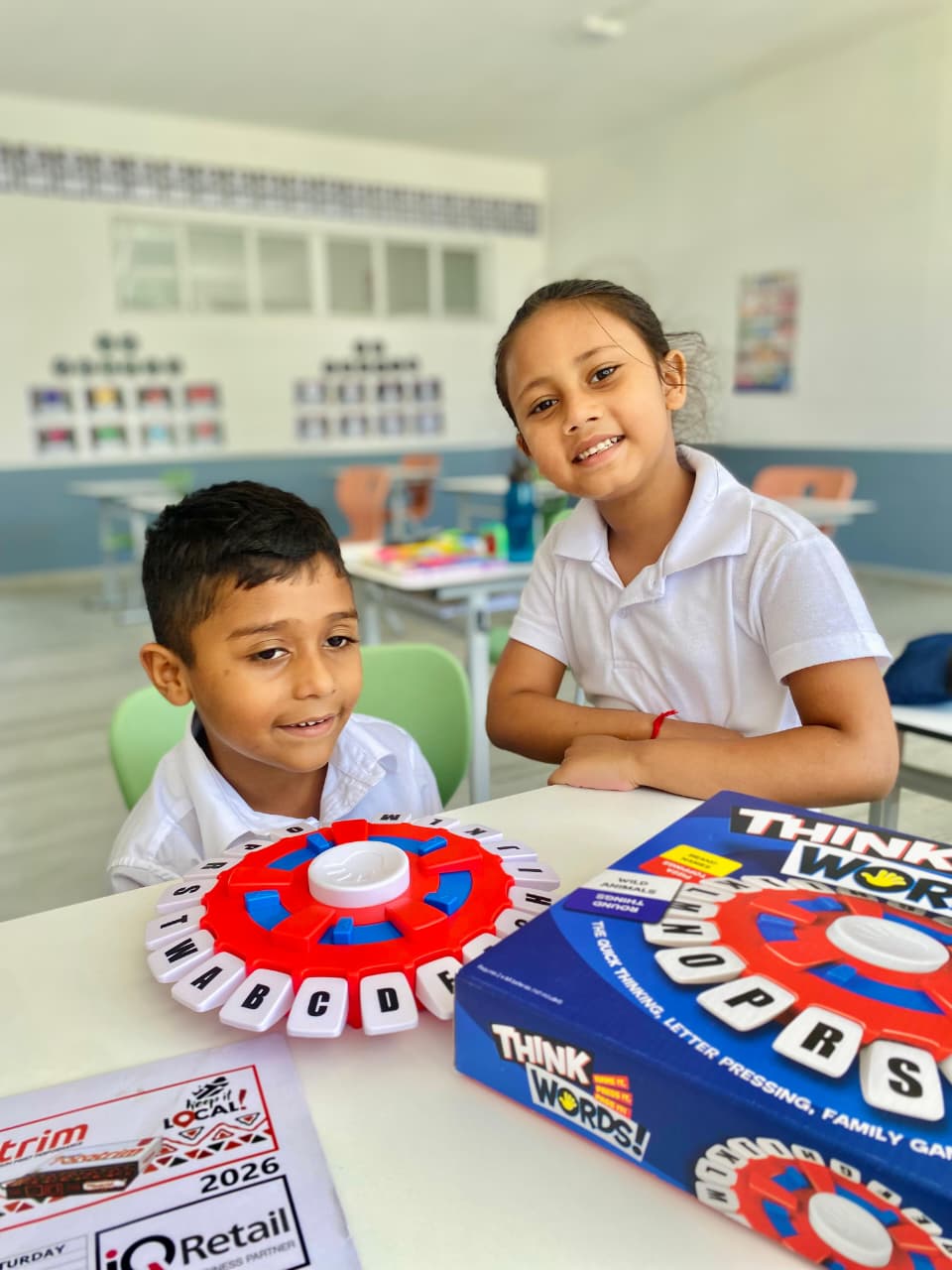 Learners smiling at a classroom desk